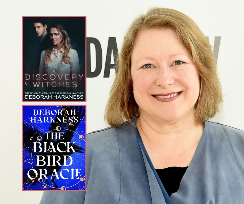 Author Deborah Harkness smiles wearing blue with her two books The Black Bird Oracle and A Discovery of Witches