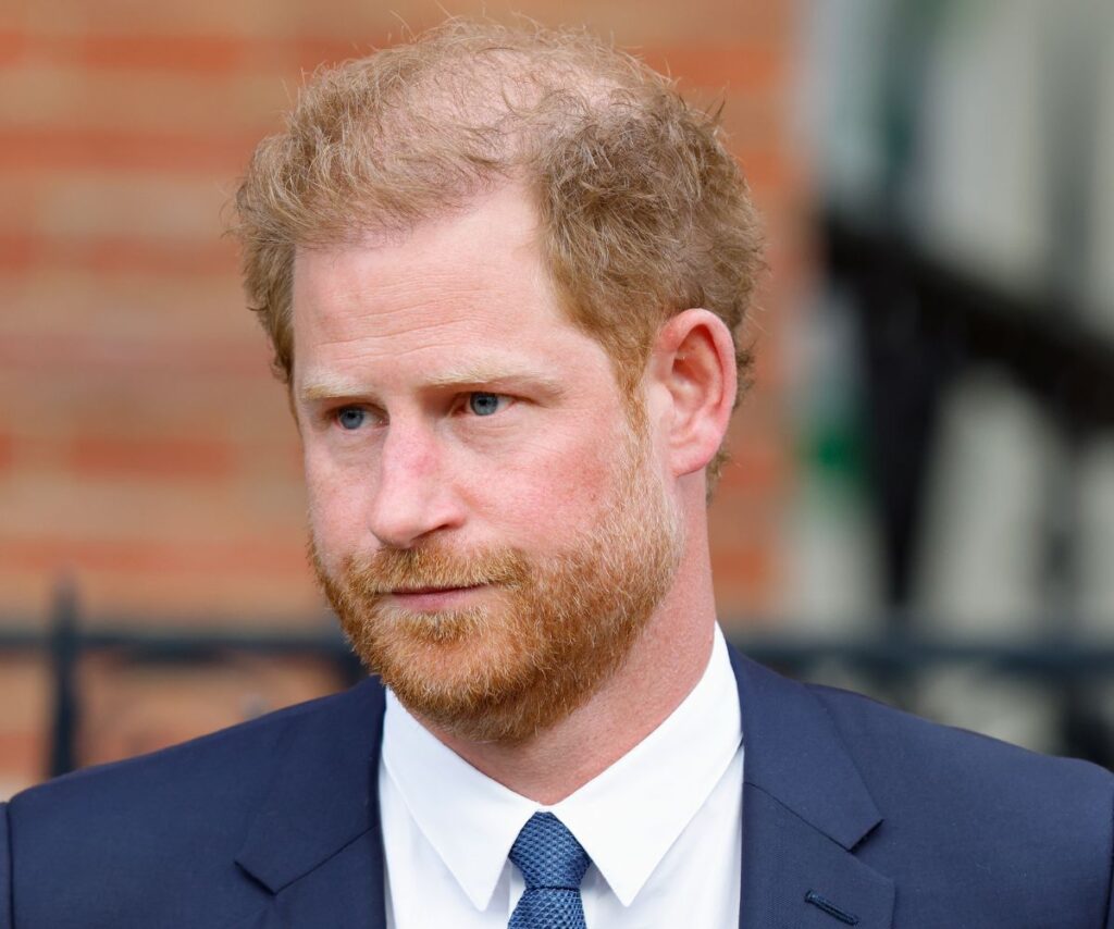 Prince Harry in blue suit looking unhappy