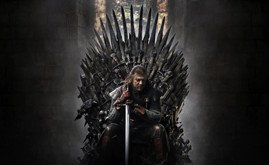 Game of Thrones Lord Eddard Stark, head of House Stark, sits on the Iron Throne, looking down with both hands on his sword, which is point down on the floor
