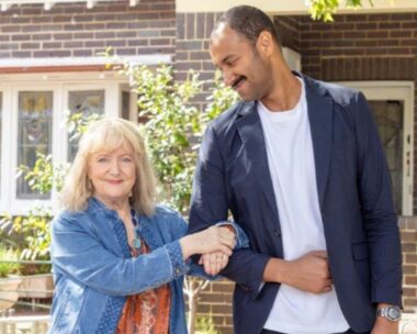 Denise Scott on Mother and Son smiling in denim jacket with arm hooked in cast member's arm