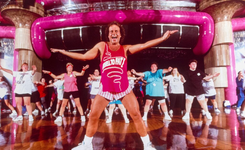 Richard Simmons leading an exercise class wearing hot pink