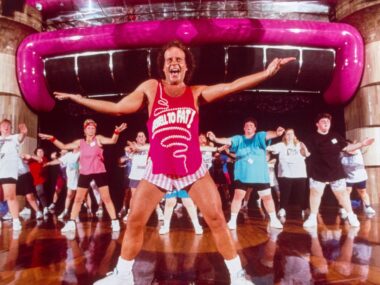 Richard Simmons leading a class in hot pink top and white tiny shorts