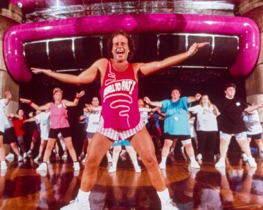 Richard Simmons leading a class in hot pink top and white tiny shorts