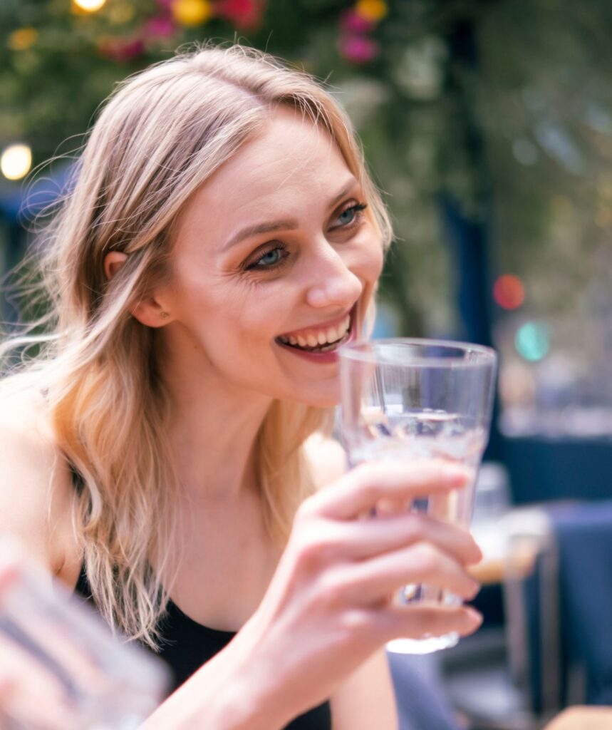 sober socialising girl with non-alcoholic drink in hand smiling