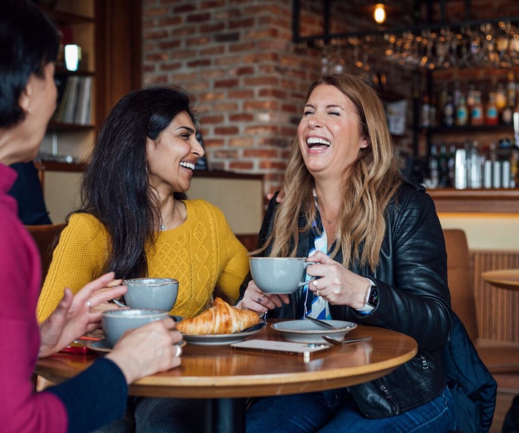women laughing around the table drinking coffee for Dry July