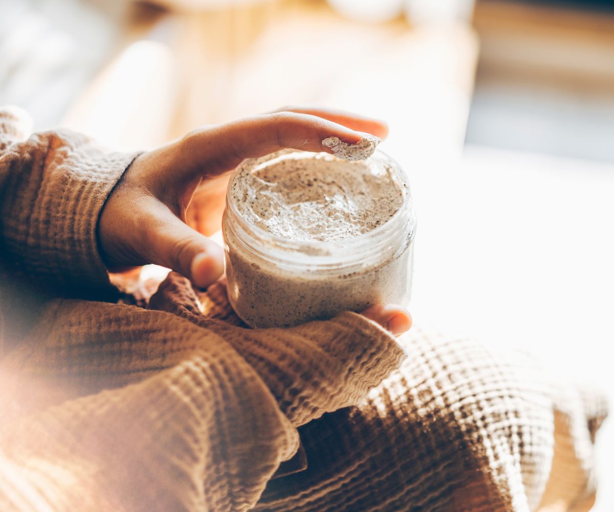 woman holding glass jar of foot scrub in winter