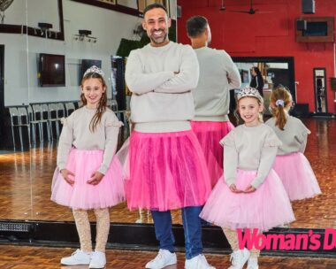 Adam Dovile stans between his daughters, all three in pink tutus and gray sweaters