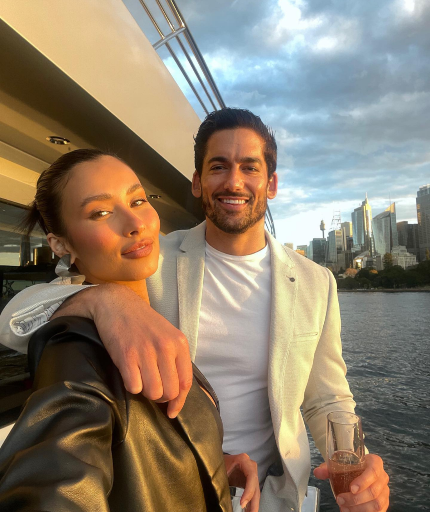 Evelyn and Duncan take a selfie on a boat during sunset's golden hour. 