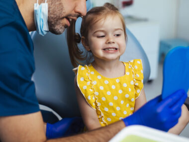 Young girl looking at a mirror after having a routine checkup at the dentist