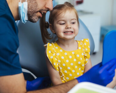 Young girl looking at a mirror after having a routine checkup at the dentist