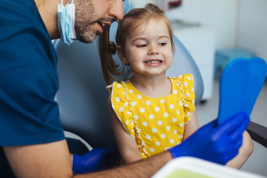 Young girl looking at a mirror after having a routine checkup at the dentist