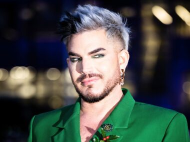 The Voice coach Adam Lambert wears green and eye liner, smirks