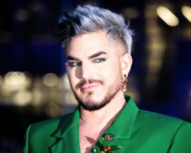 The Voice coach Adam Lambert wears green and eye liner, smirks