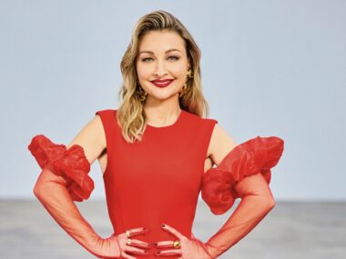 The Voice coach Kate Miller Heidke smiles in a red dress with hands on hips