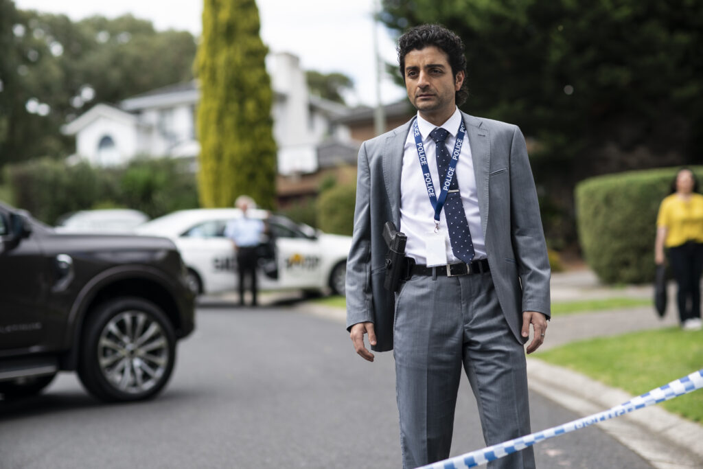 Detective Jarred (Rahel Romahn) is standing in the street, near the crime scene.