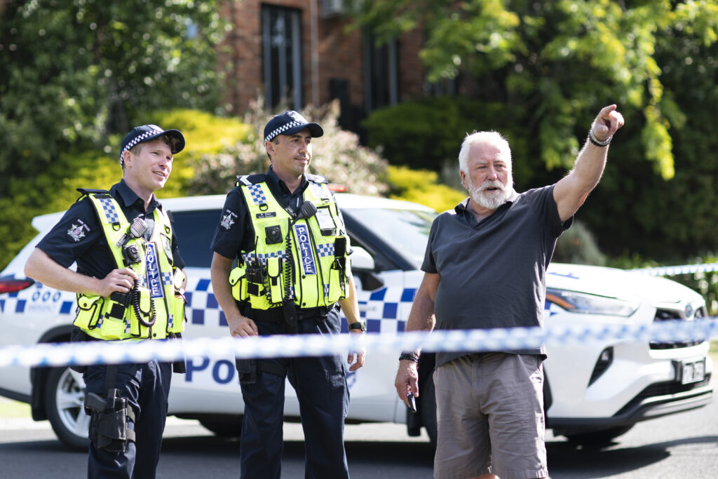 Holly's father Bear (Steve Bisley) is pointing out something to two police officers.