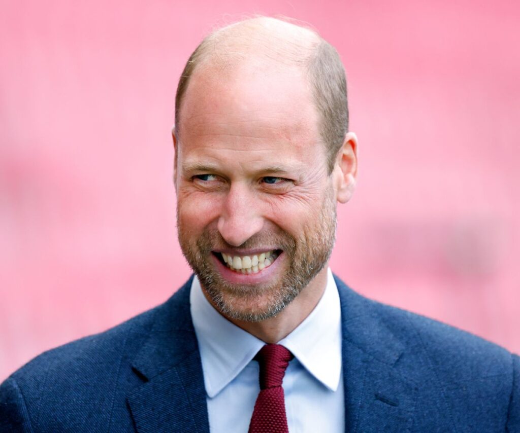 Prince William with a beard smiling and laughing.