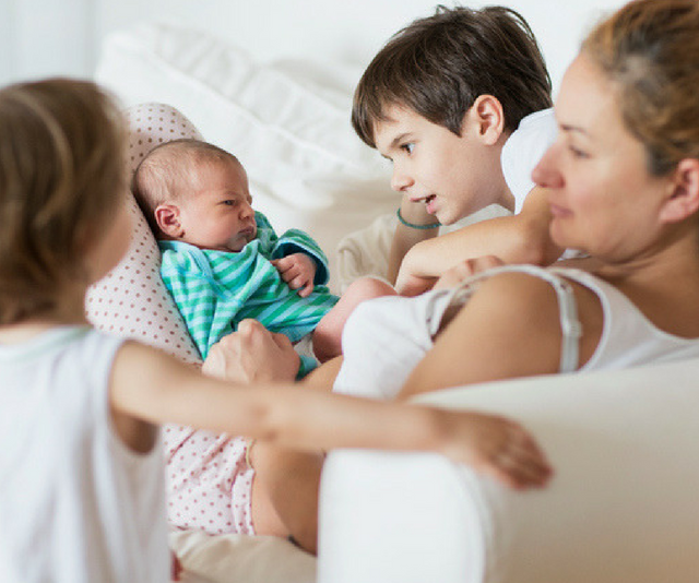 Mother and children including newborn on relaxing on sofa